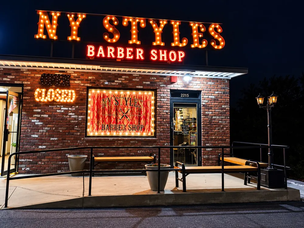 NY Styles Barbershop storefront lit up at night at 2215 NY-112 in Medford, NY